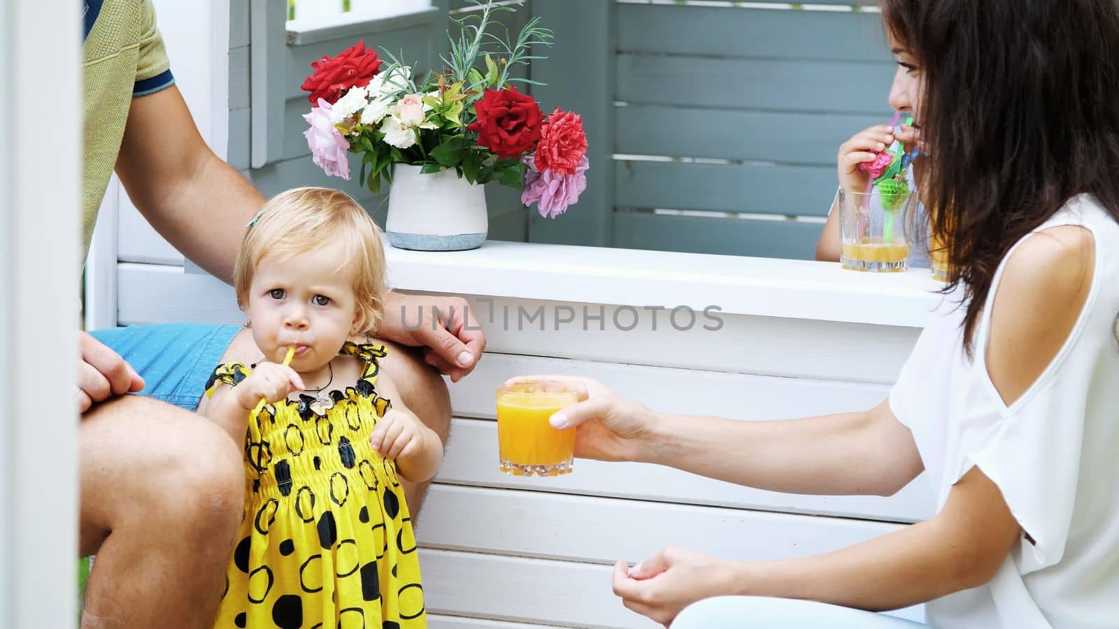 summer, in the garden, parents play with young children, a girl and a boy, in a cafe, in a children's play house, treat children with freshly squeezed fruit juices, drink juices. by djtreneryay