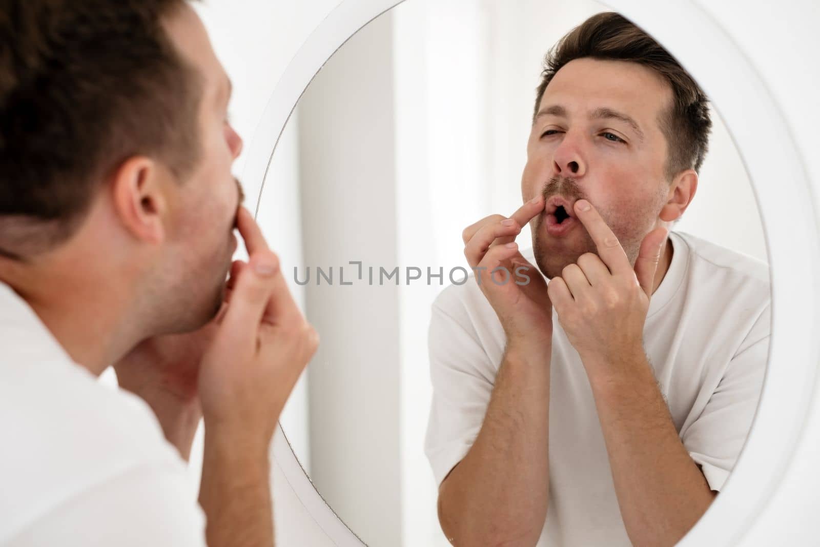 Selfish young caucasian man trying to cheer himself up before a first date looking at the mirror 