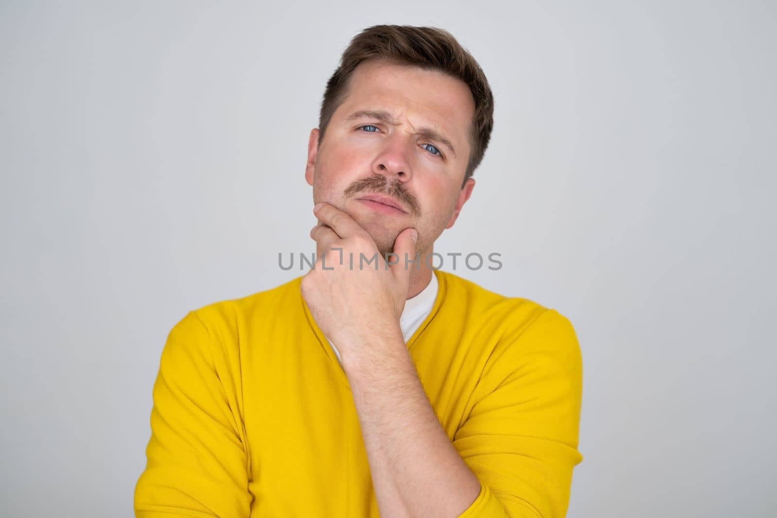 Thoughtful caucasian young man touch chin with finger thinking or considering, pensive European man making decision or imagining