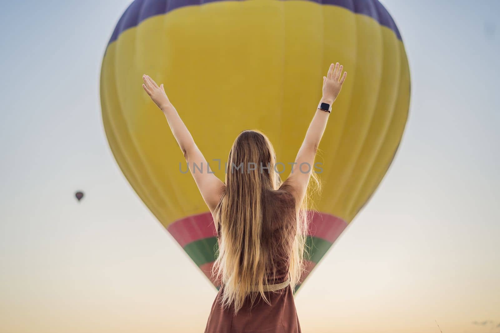 Tourist woman looking at hot air balloons in Cappadocia, Turkey. Happy Travel in Turkey concept. Woman on a mountain top enjoying wonderful view.