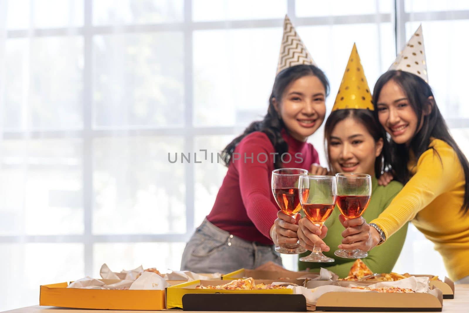 Group of happy young Asian people with friends celebrating clinking glasses during dinner party by wichayada