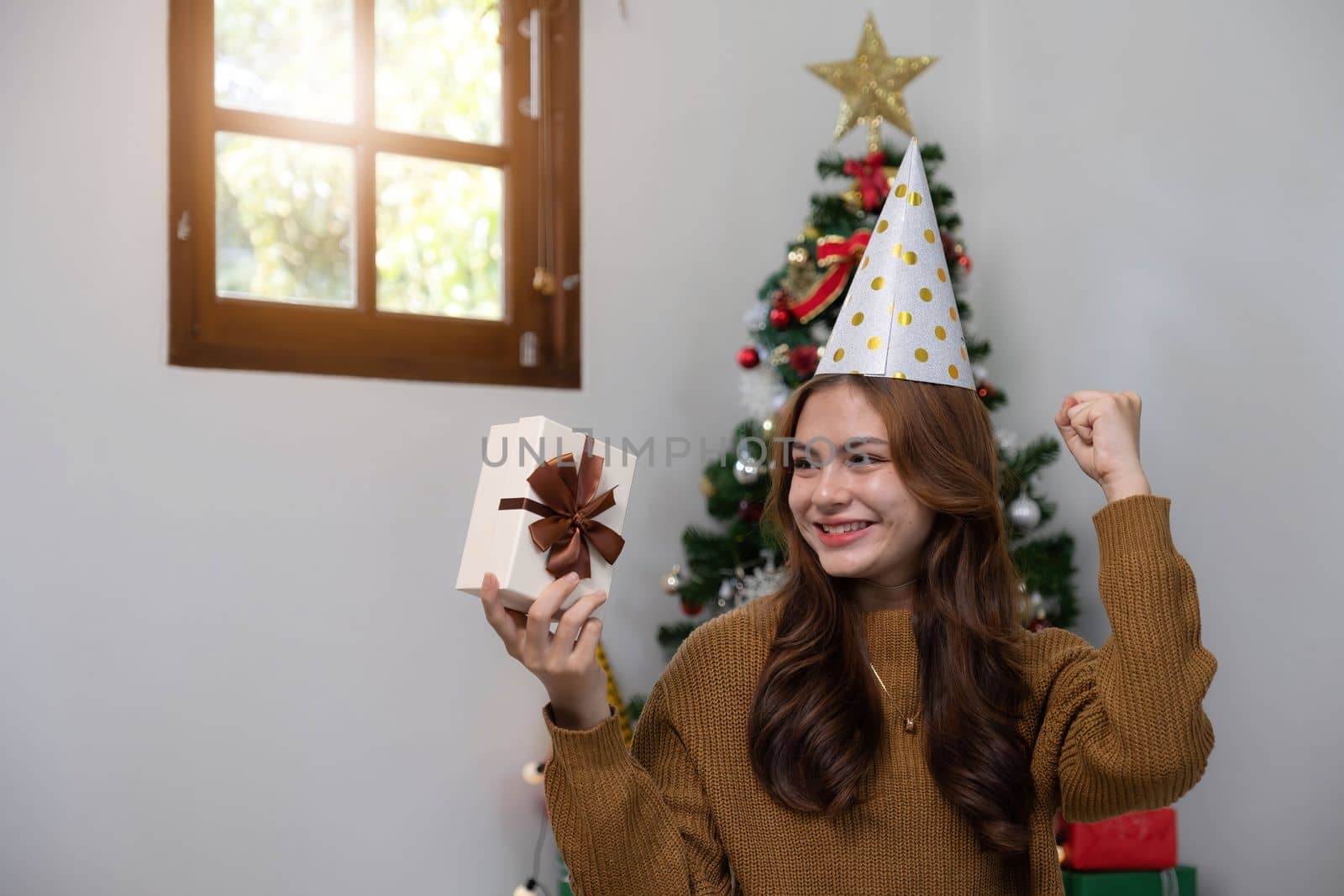 Merry Christmas and Happy Holidays Young woman with a beautiful face in a yellow shirt shows joy with gift boxes in a house