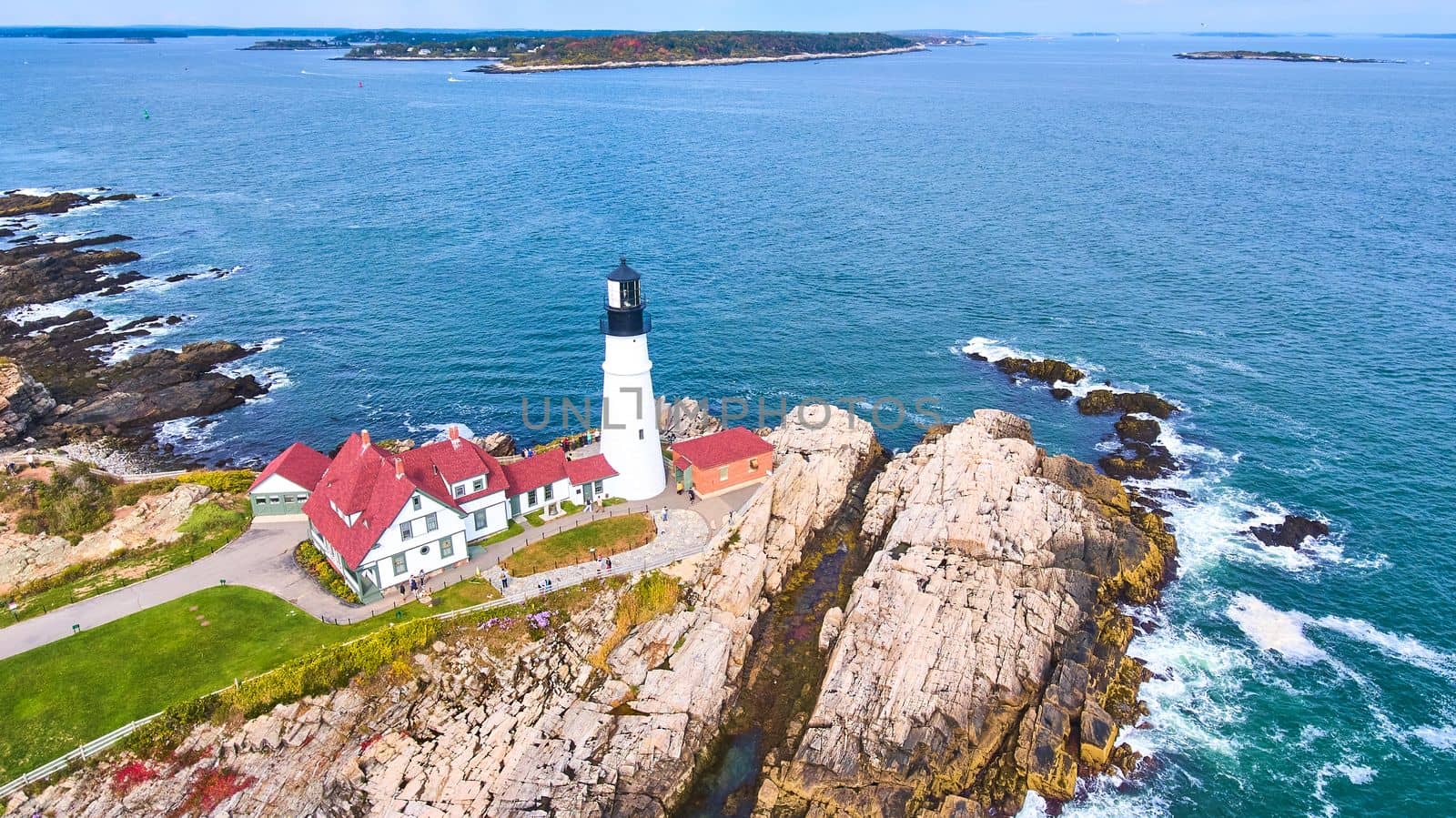 Image of Aerial overlooking amazing Portland lighthouse in Maine with rocky coasts and crashing waves