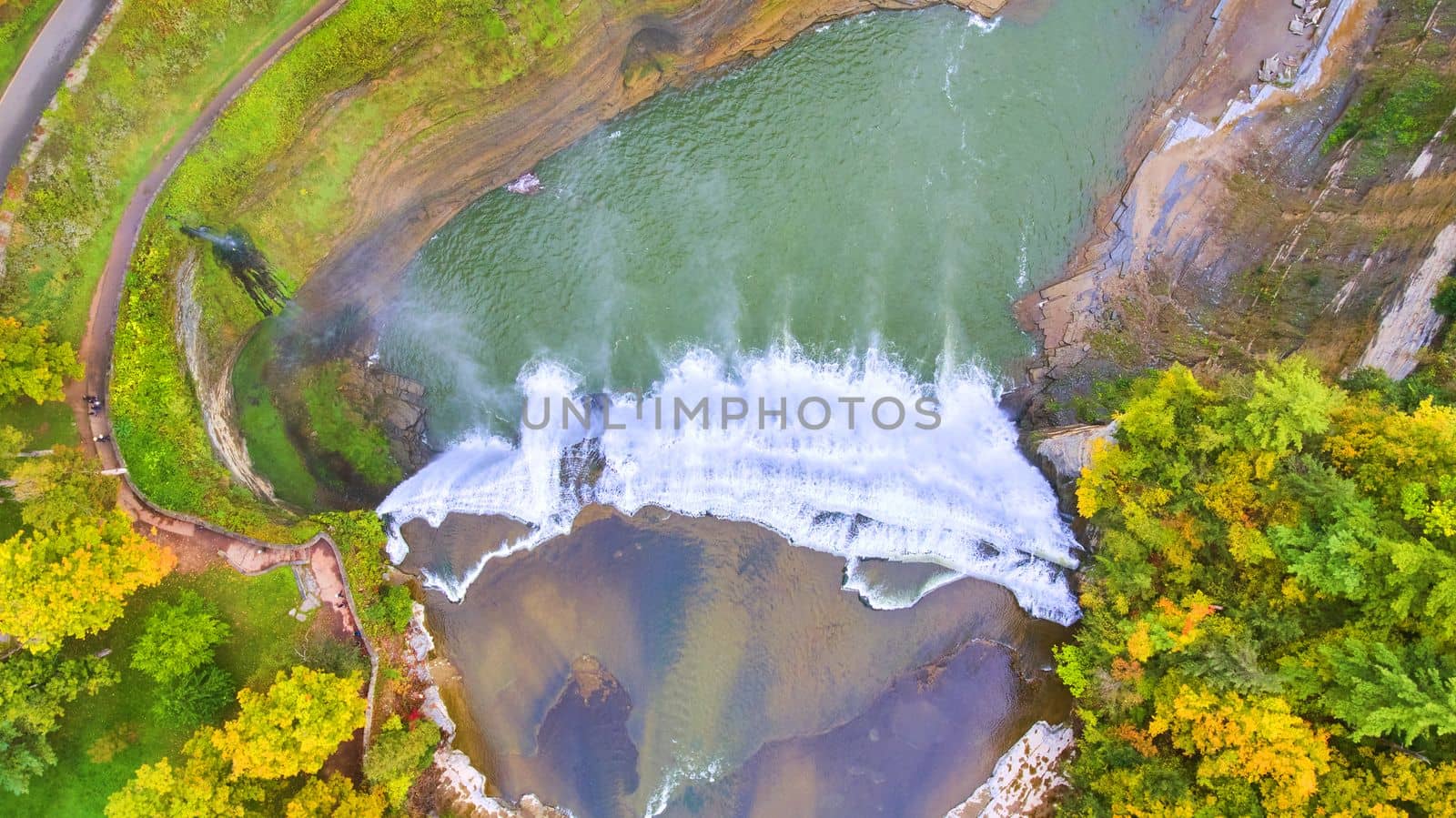 Aerial straight down over huge raging waterfall in canyon with trail along left side for viewing by njproductions