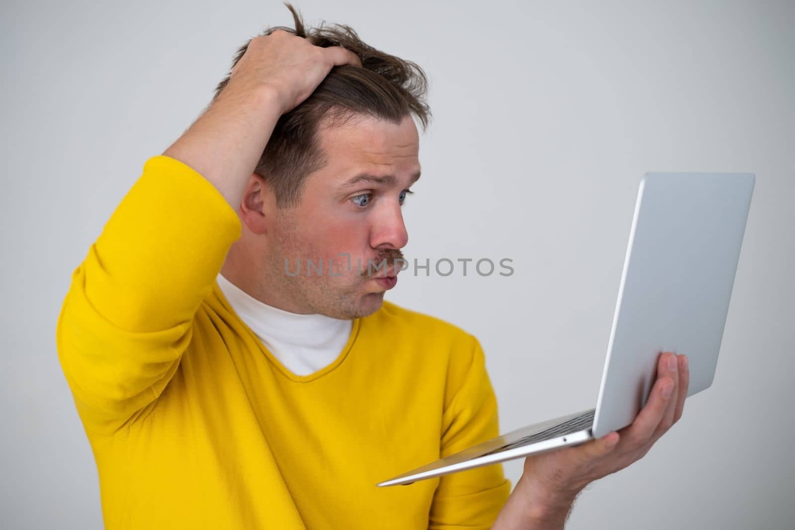 Thinking young man standing with laptop looking on screen with confused puzzled face. I have forgotten my password concept