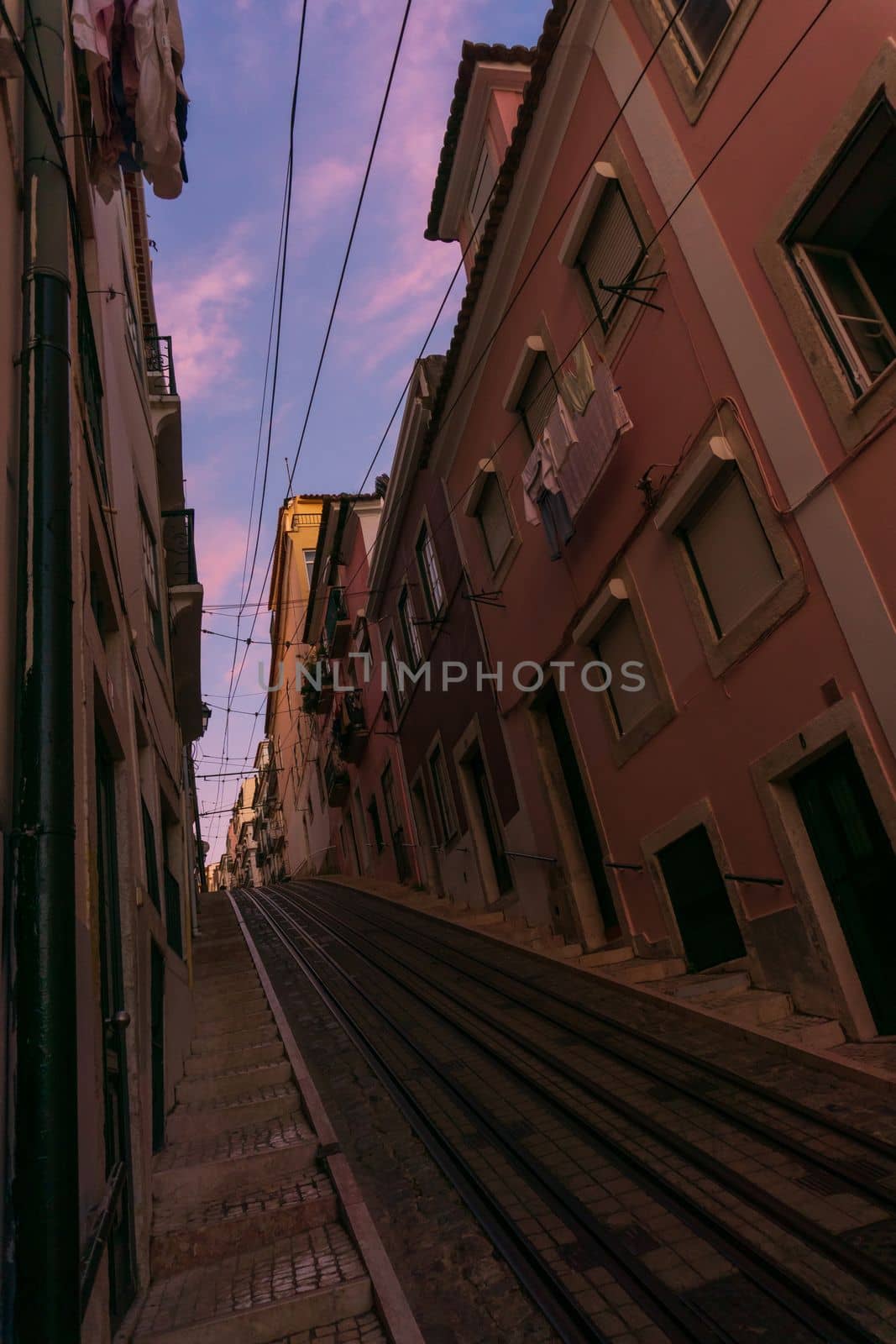 Narrow street with rails in Lisbon at sunset