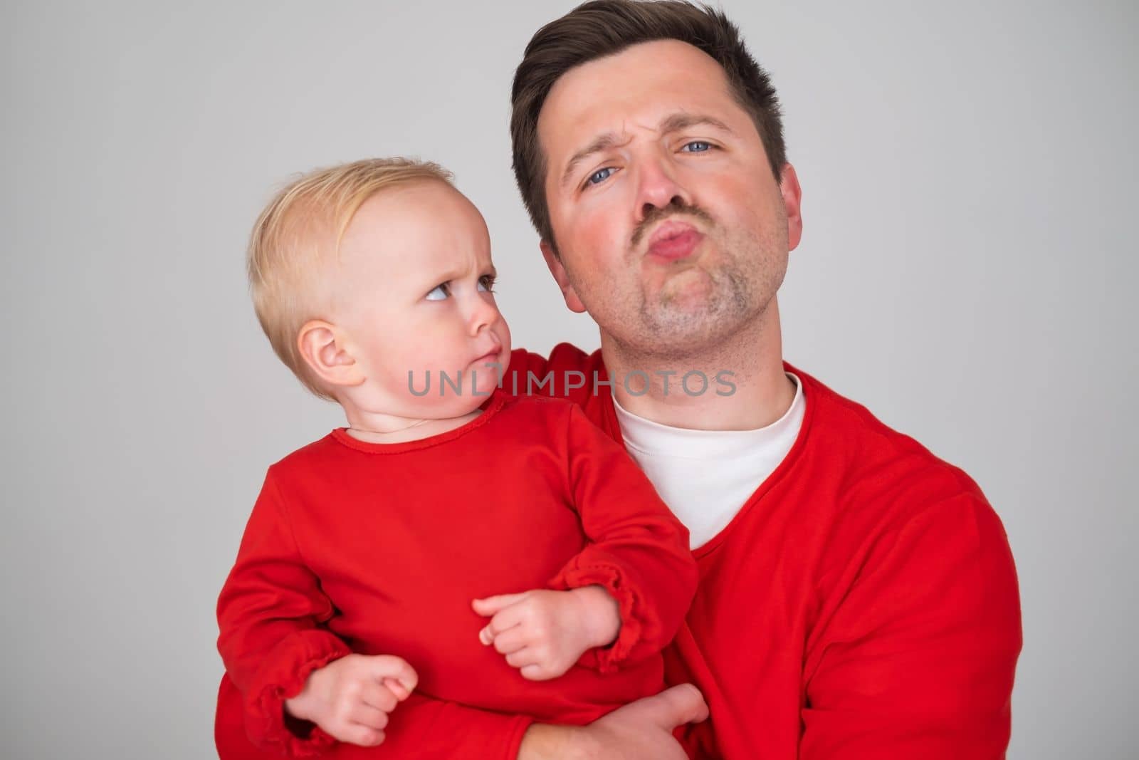 happy father holding his baby daughter smiling at camera. Studio shot