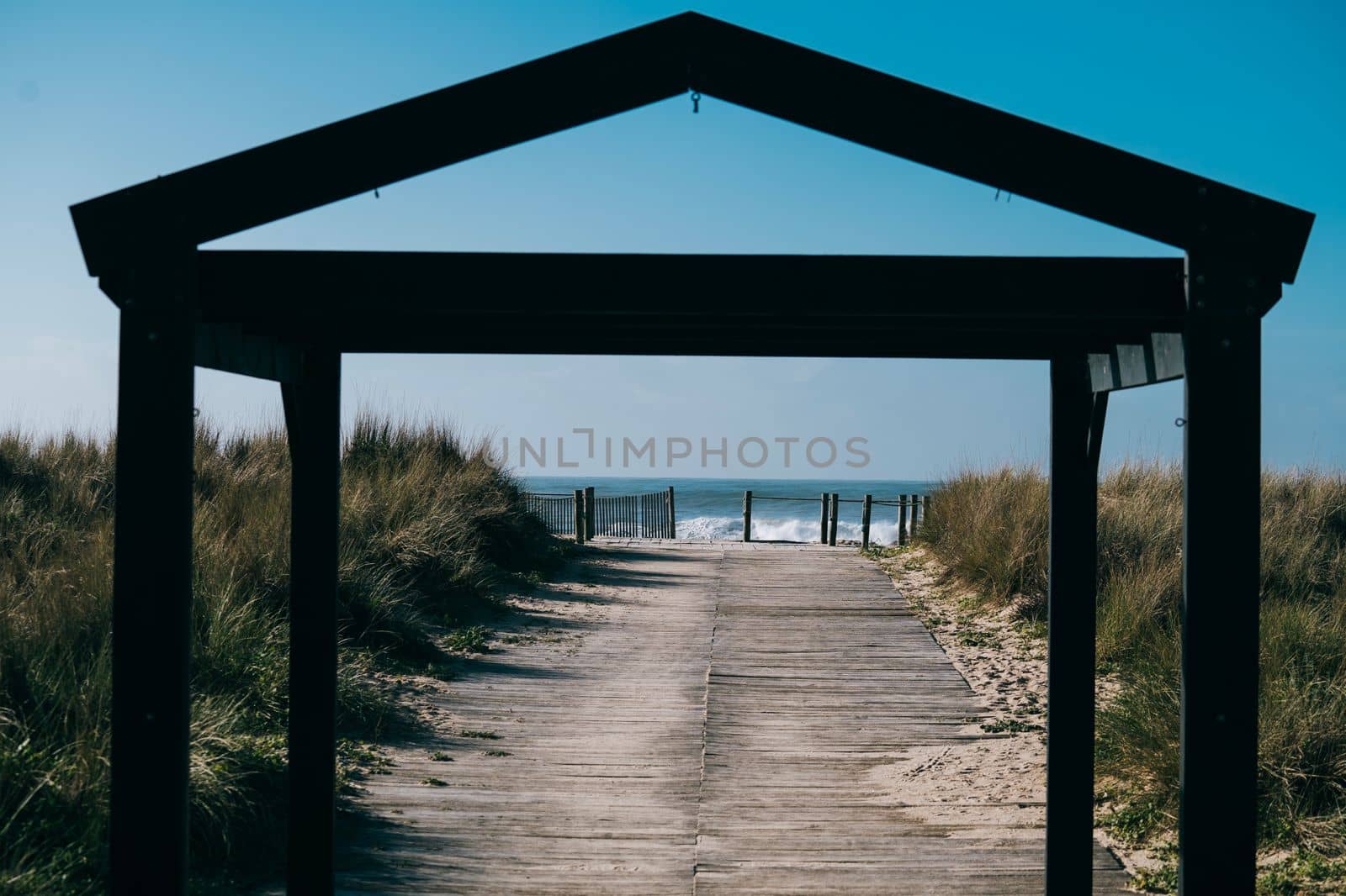 Gate to the beach with sea waves in background on sunny day.