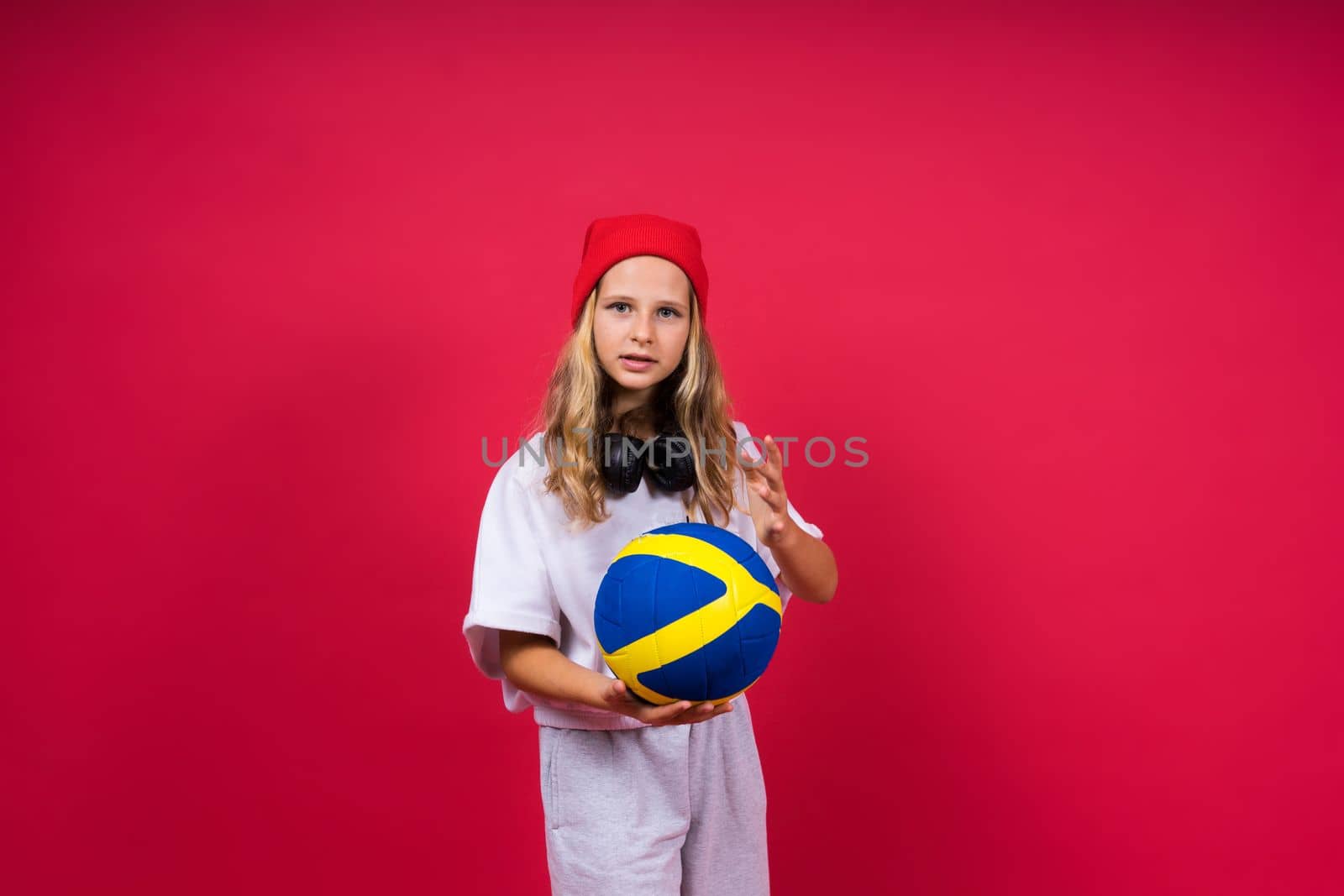 Portrait of cute eight year old girl in volleyball outfit isolated on a red background