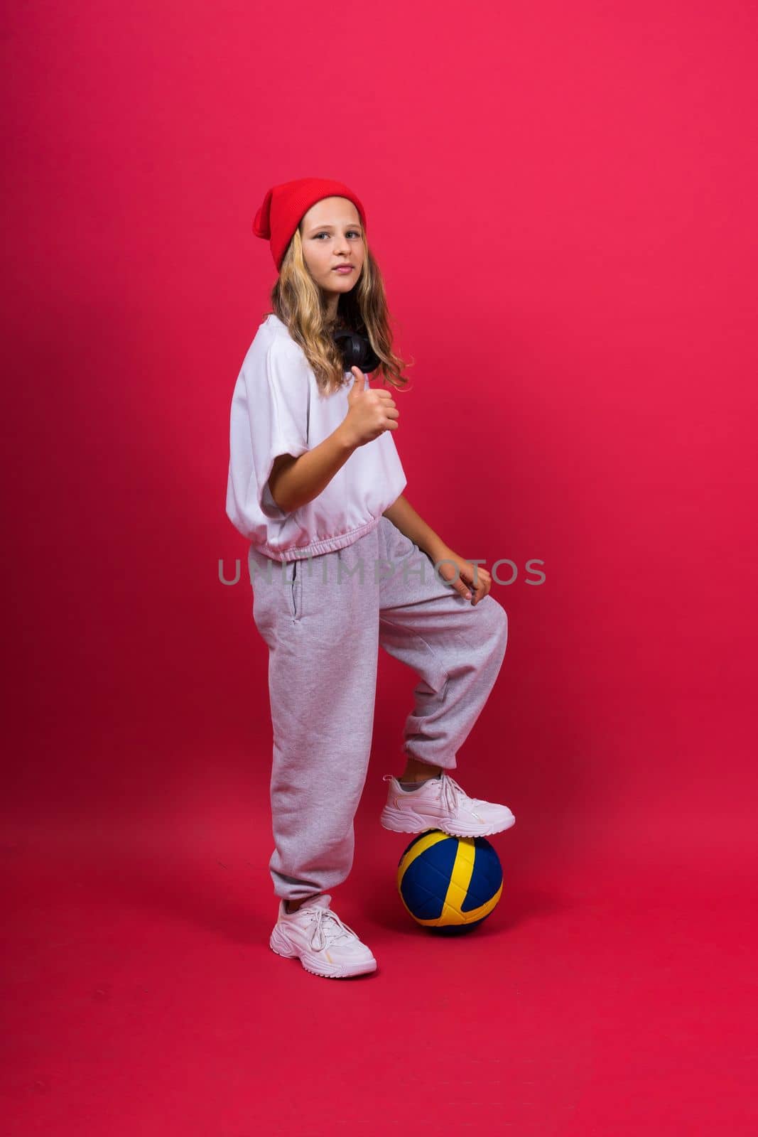 Portrait of a cute eight year old girl in volleyball outfit isolated on a red background by Zelenin