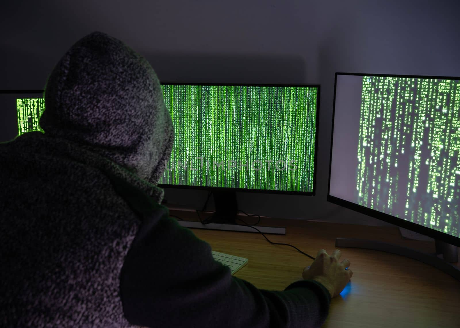 Anonymous Hacker male with hood using his skills to break security systems in internet.