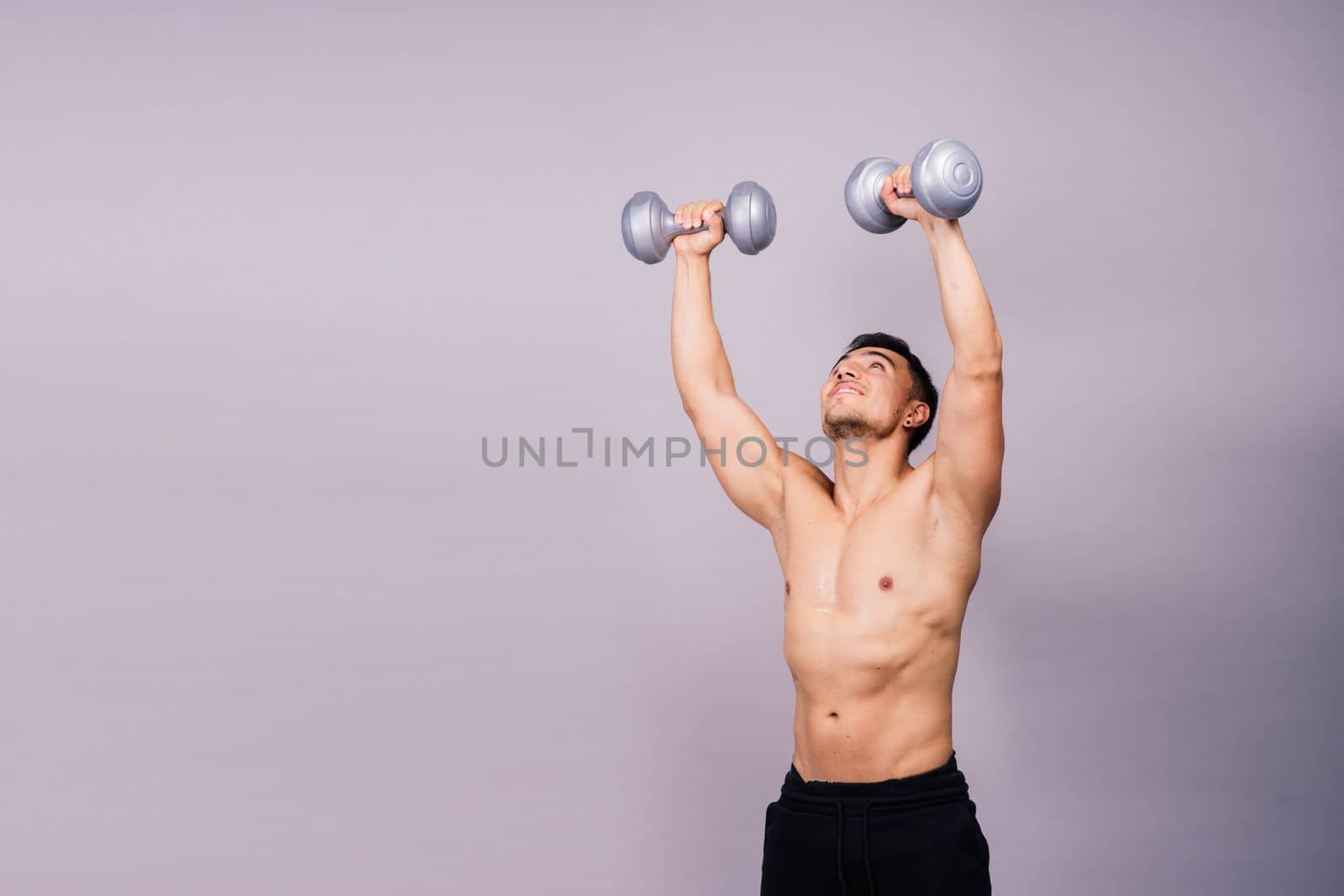 Shirtless bodybuilder showing his great body and holding dumbells.