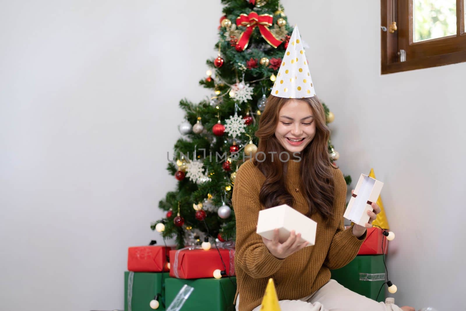 Merry Christmas and Happy Holidays Young woman with a beautiful face in a yellow shirt shows joy with gift boxes in a house