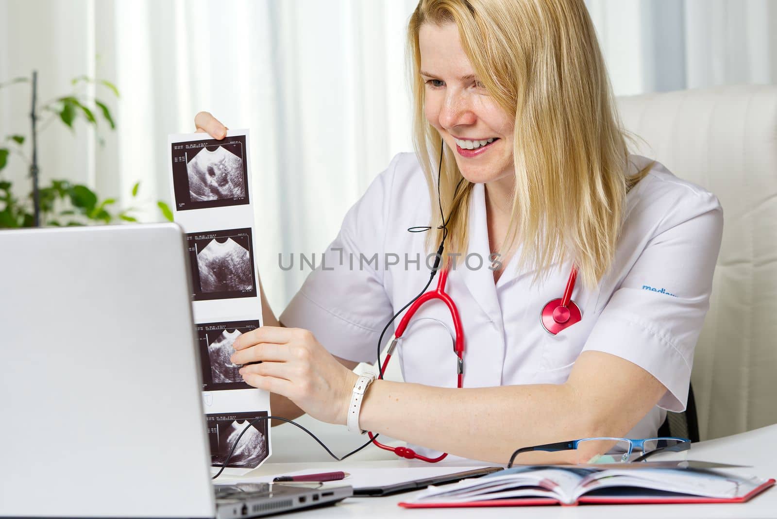 Female doctor showing her patient picture of ultrasound image of her baby on the laptop teletreatment by PhotoTime