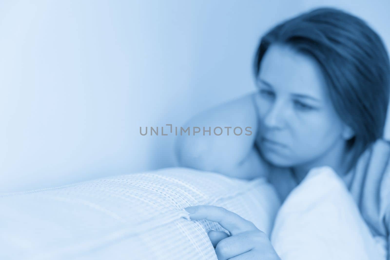 sad woman sitting on the bed holding pillow by Mariakray