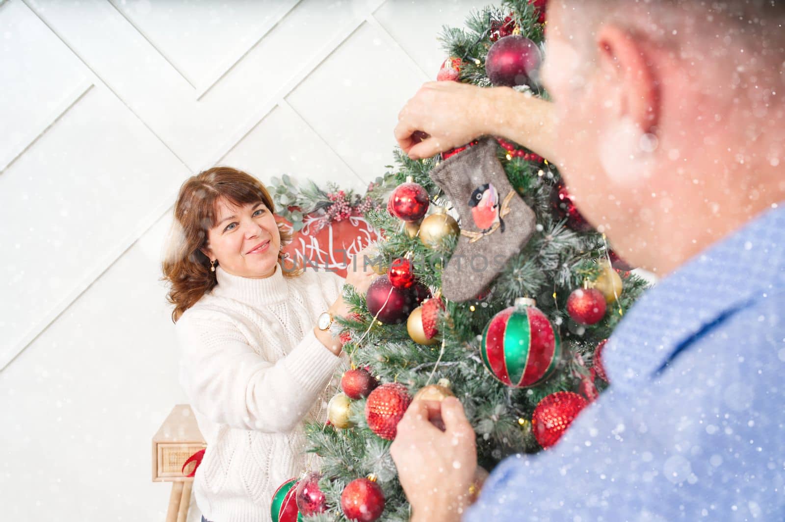 Smiling happy middle age couple decorating christmas tree at home. Happy couple together at home, christmas concept by PhotoTime