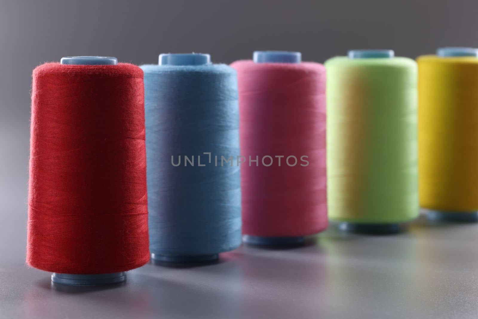 Multicolored thread spools on gray background. Set of colored threads concept