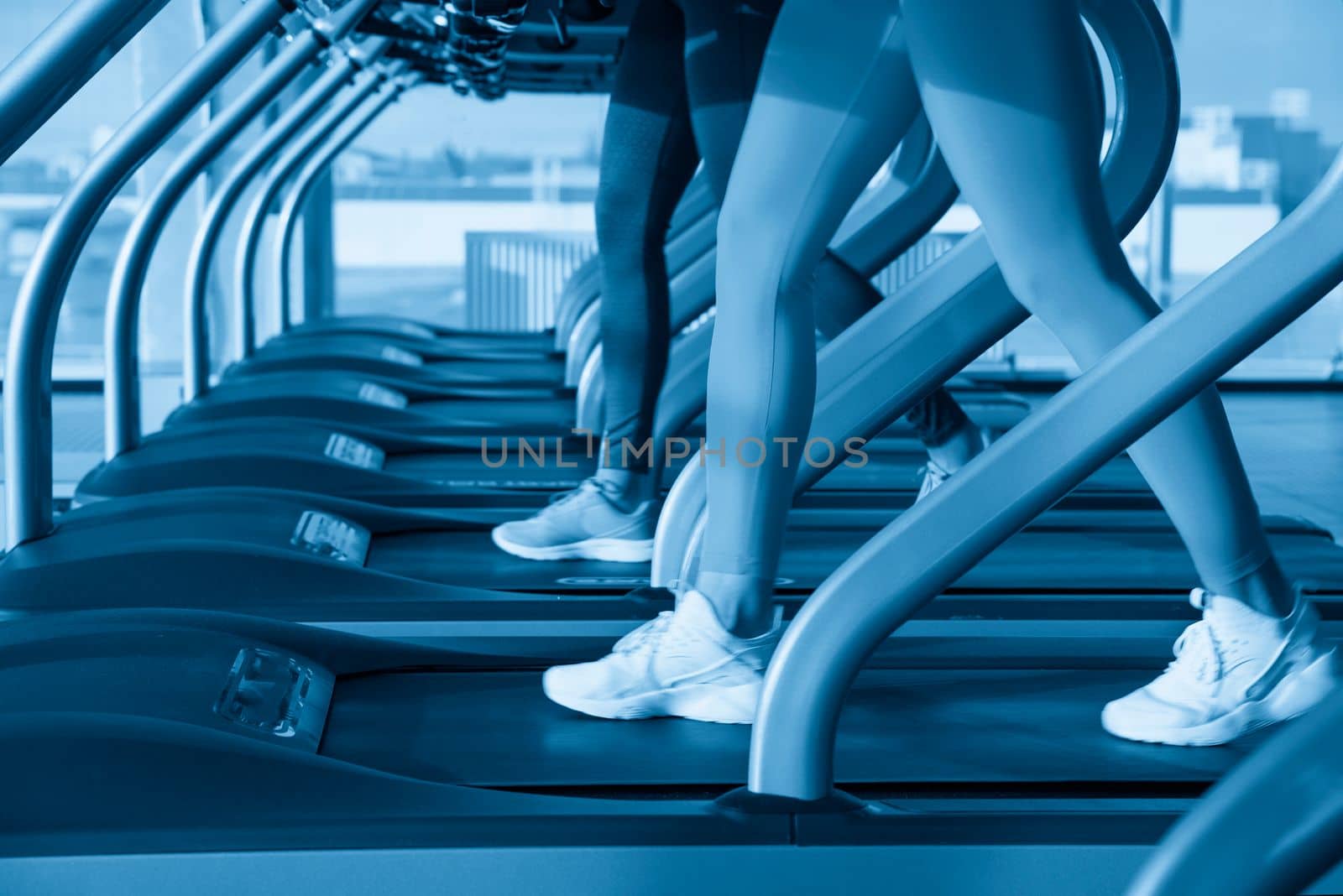 Two young women running on treadmill in a gym