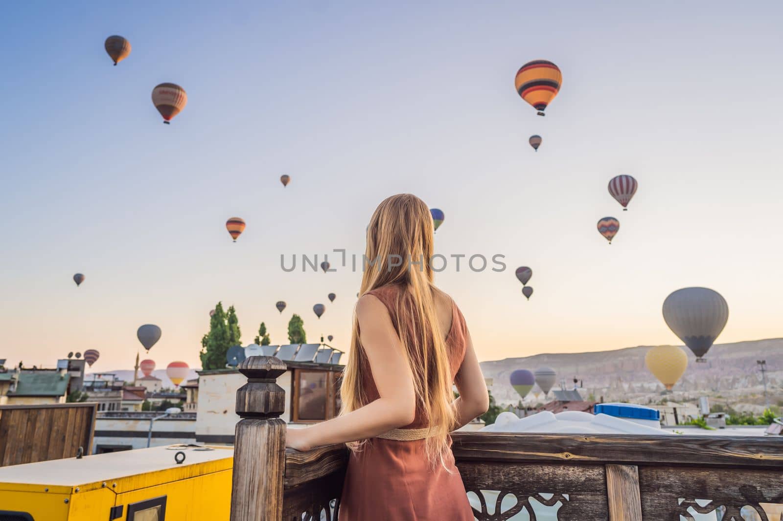 Tourist woman looking at hot air balloons in Cappadocia, Turkey. Happy Travel in Turkey concept. Woman on a mountain top enjoying wonderful view.