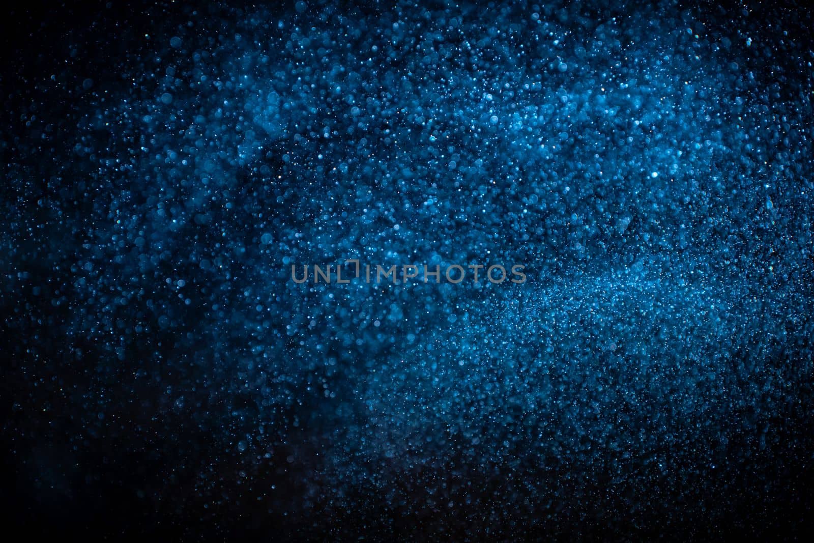 Abstract real blue dust particles on black background. Glittering sparkling bokeh overlay design with copy space for text. High quality photo