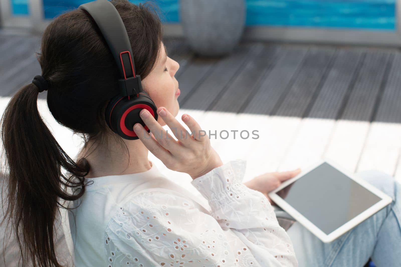 Sad girl listens to music from a tablet at a table in a cafe, High quality photo