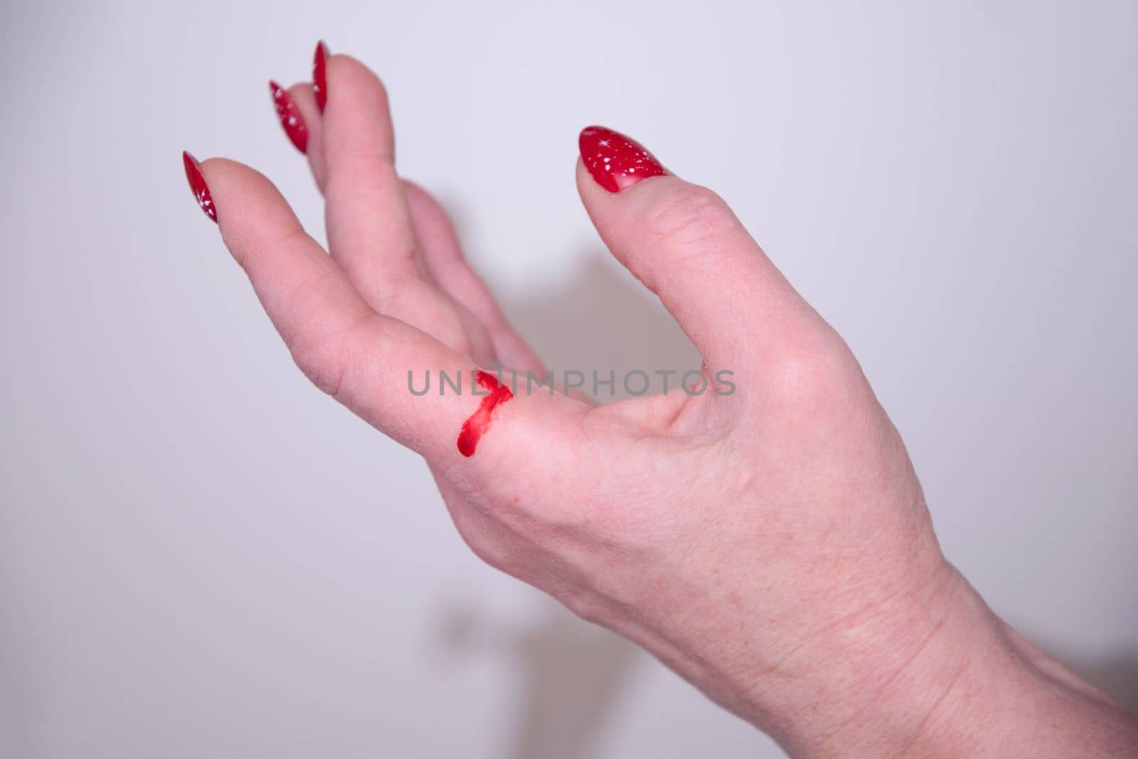 woman cut her hand with paper and gift wrapping red blood on her hand by KaterinaDalemans