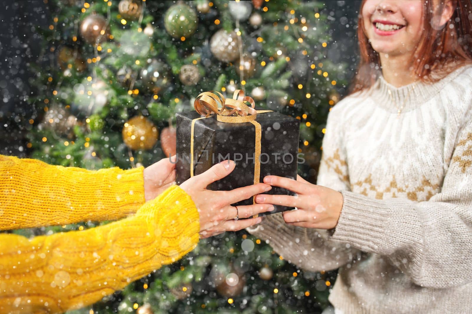 Smiling mother gives her daughter a christmas present. Happy family sharing joy with each other. by PhotoTime