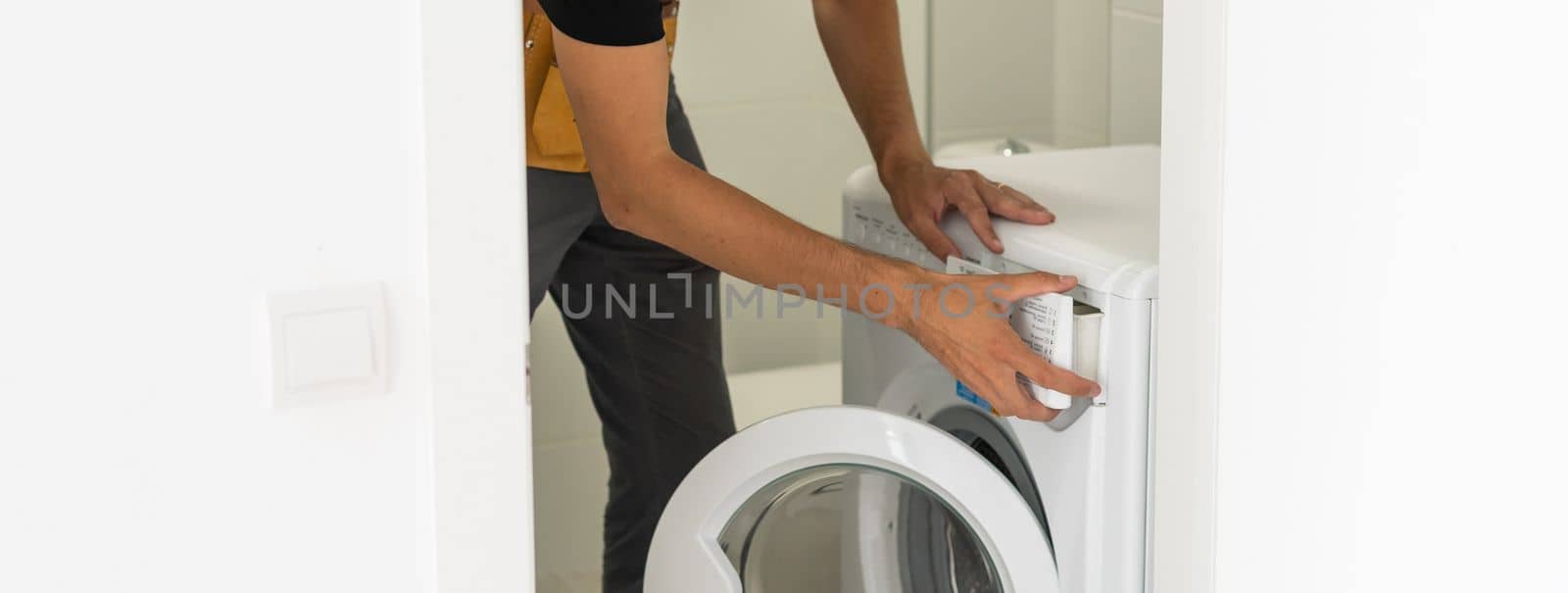 Young attractive smiling worker in uniform fixing washing machine