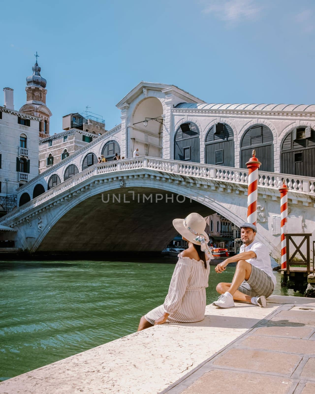 Venice Italy couple men and woman on a city trip to Venice, men and woman at the waterfront looking at the famous Rialto bridge in Venice Italy. Europe