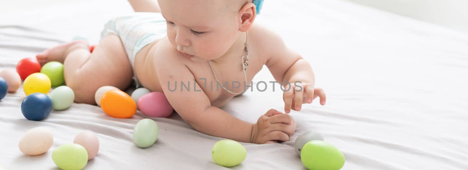 Portrait of a cute baby dressed in Easter bunny ears with a basket full of eggs by Andelov13