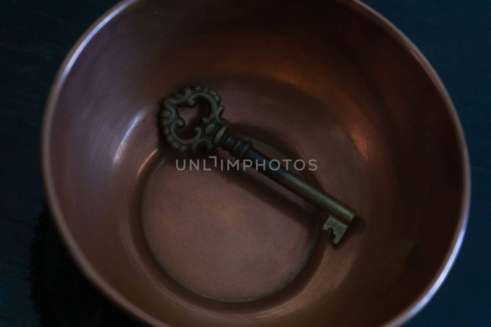 Antique metal key in antique copper bowl close up