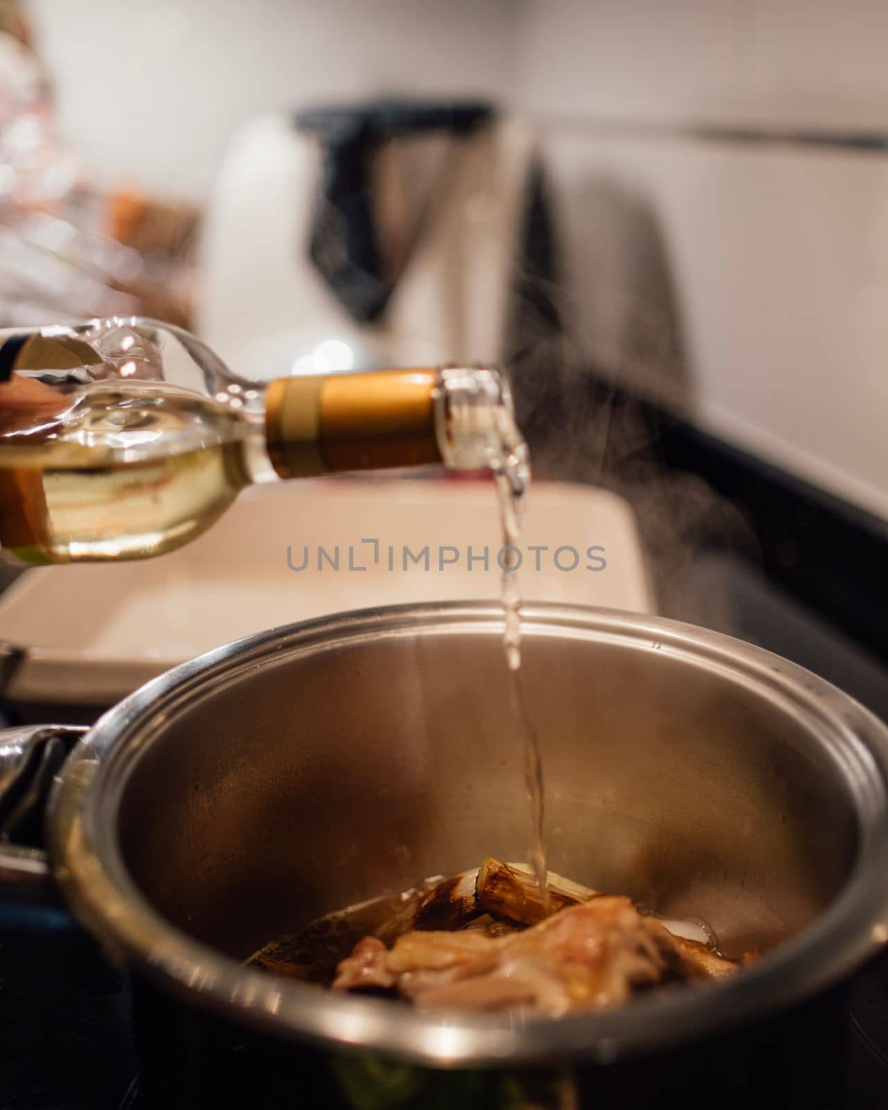 Woman adding white wine on a cooking pot. Preparing chicken soup.