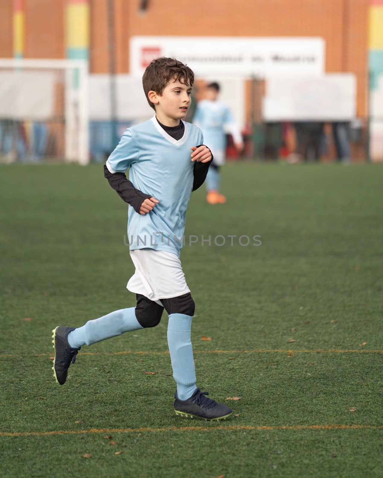 Portrait of young boy play on the grass football field in the stadium during a match in cold weather.