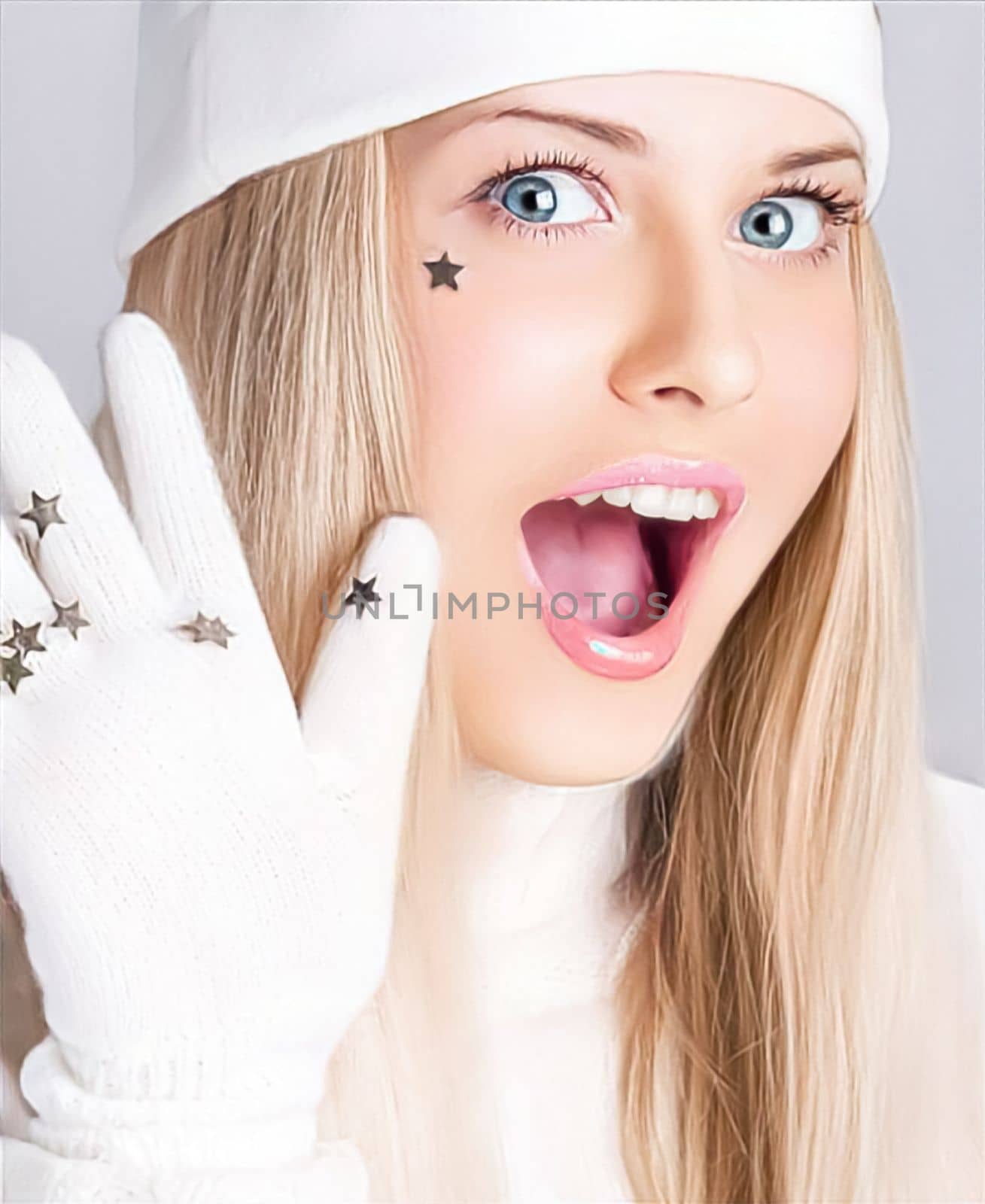 Greetings from a woman in a white hat and gloves and a merry holiday season. Beautiful female model against studio background at festive event. Laughing and loving the lifestyle of the holidays, surprised blonde girl smiles.