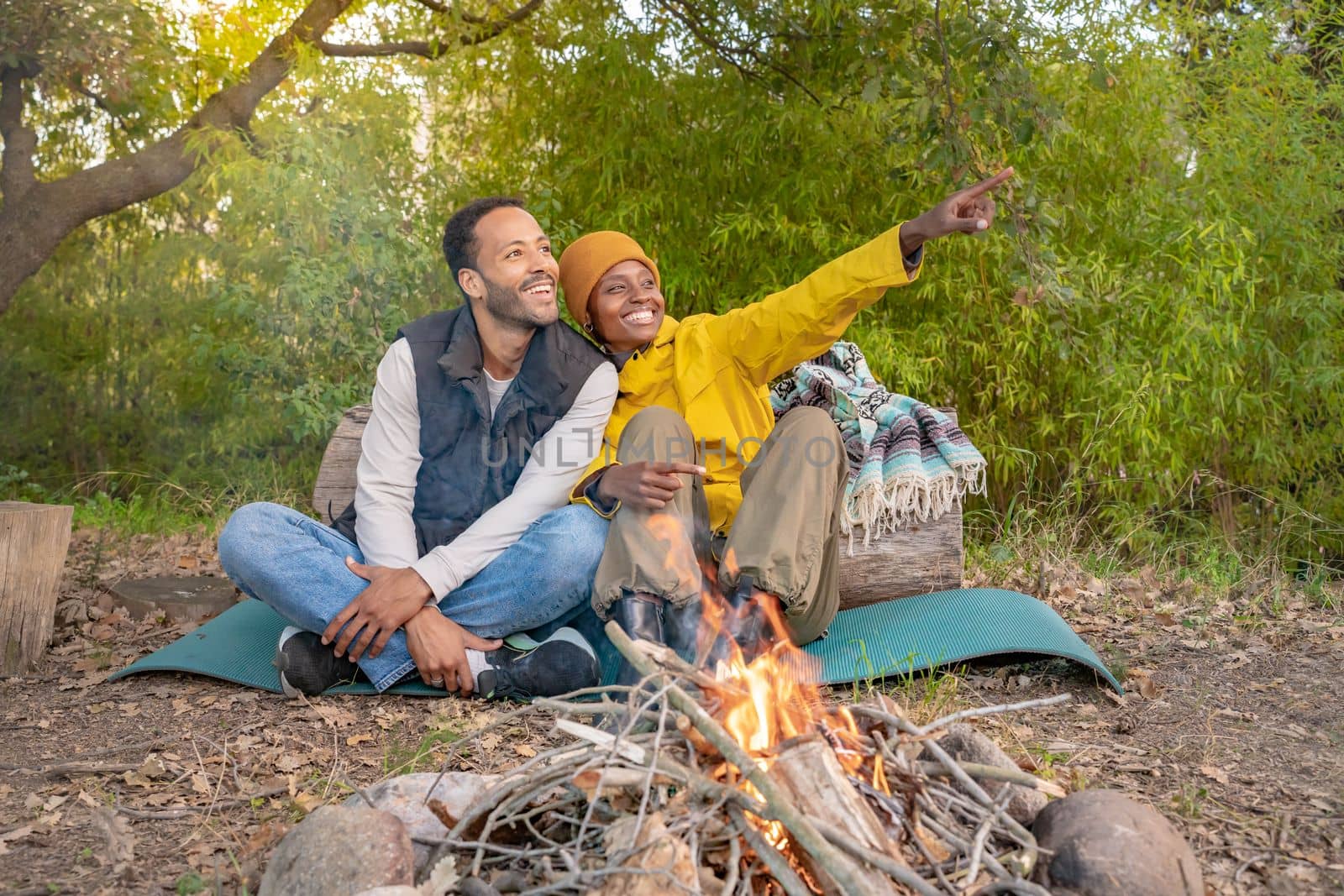 Multiethnic couple sitting outside around camp fire. Enjoying nature healthy life. High quality photo