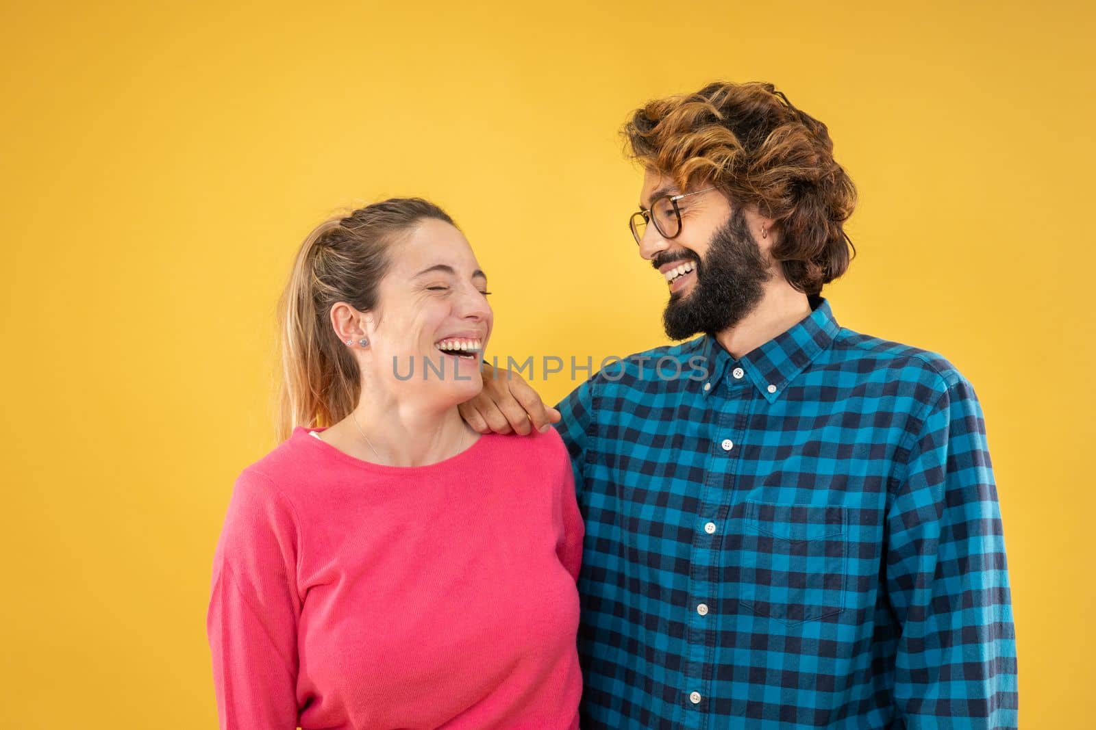 Young couple of man and woman laughing, smiling, happy isolated on yellow color background having fun together. High quality photo