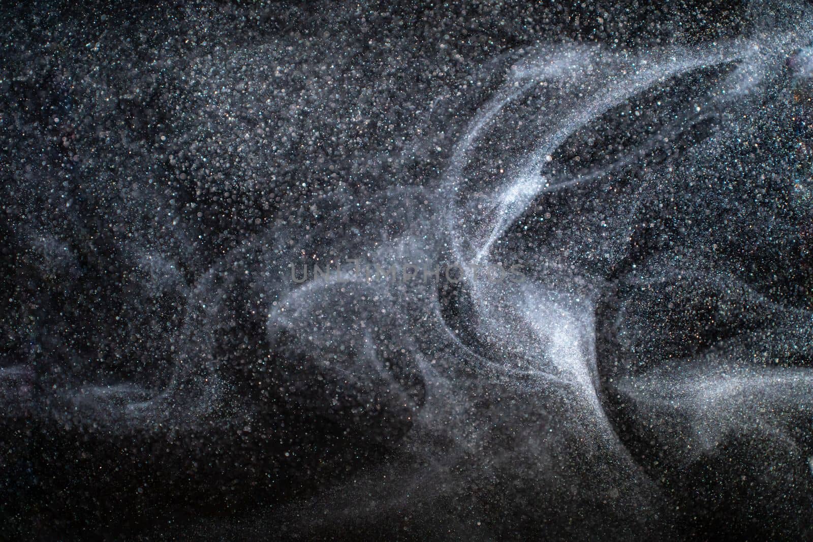 Dust particles cloud generating abstract shapes with black background and copy space for text. Beautiful organic natural elements for designs. High quality photo
