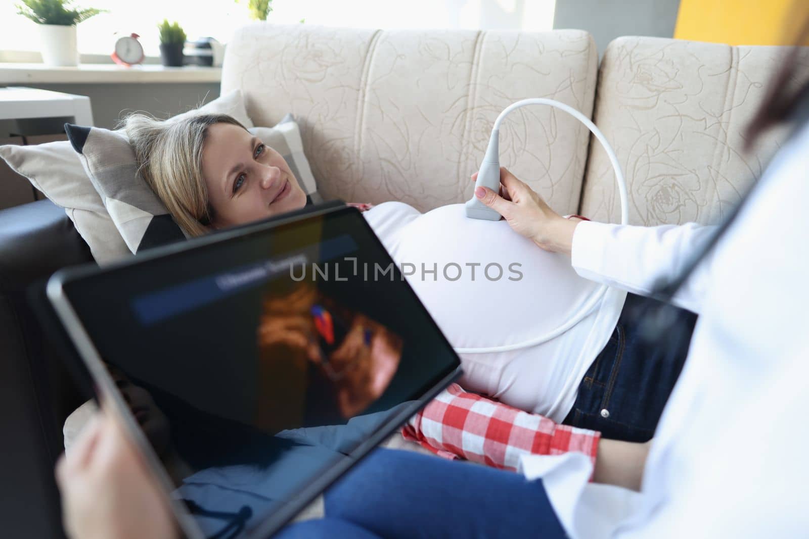 Gynecologist conducts ultrasound of pregnant woman at home. Examination of fetus of child concept