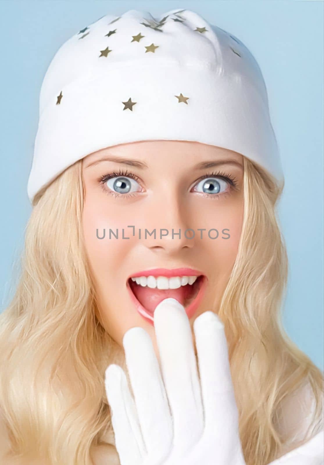 Girl with blond hair and blue eyes seems surprised and amused while smiling and enjoying the winter holiday season lifestyle.