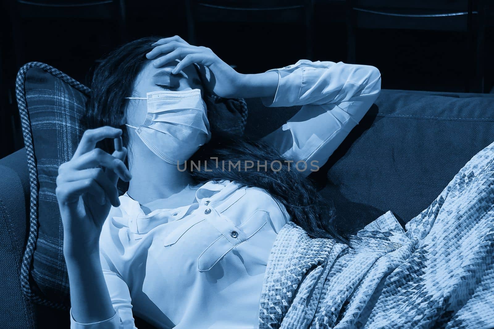 young woman on sofa covered with a blanket freezing blowing running nose got fever, caught, sick girl having influenza symptoms, flu or virus concept by Mariakray