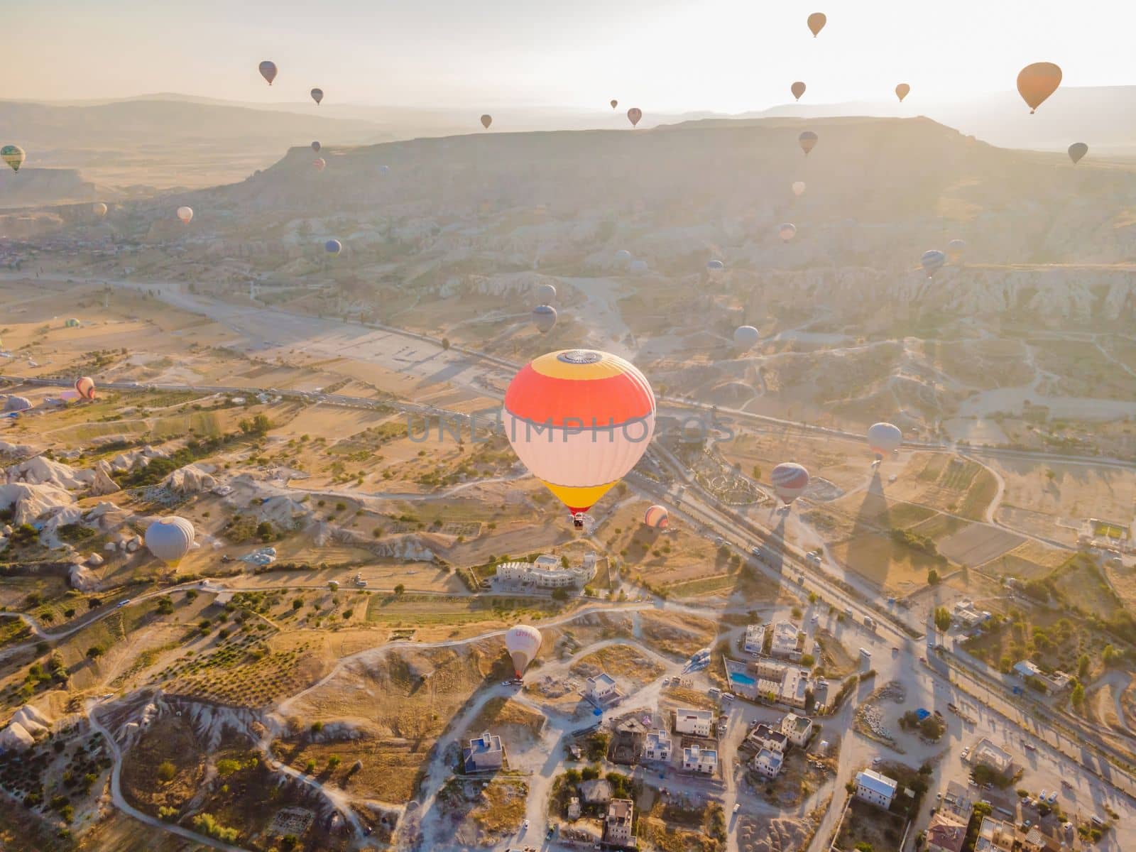 Colorful hot air balloons flying over at fairy chimneys valley in Nevsehir, Goreme, Cappadocia Turkey. Spectacular panoramic drone view of the underground city and ballooning tourism. High quality by galitskaya