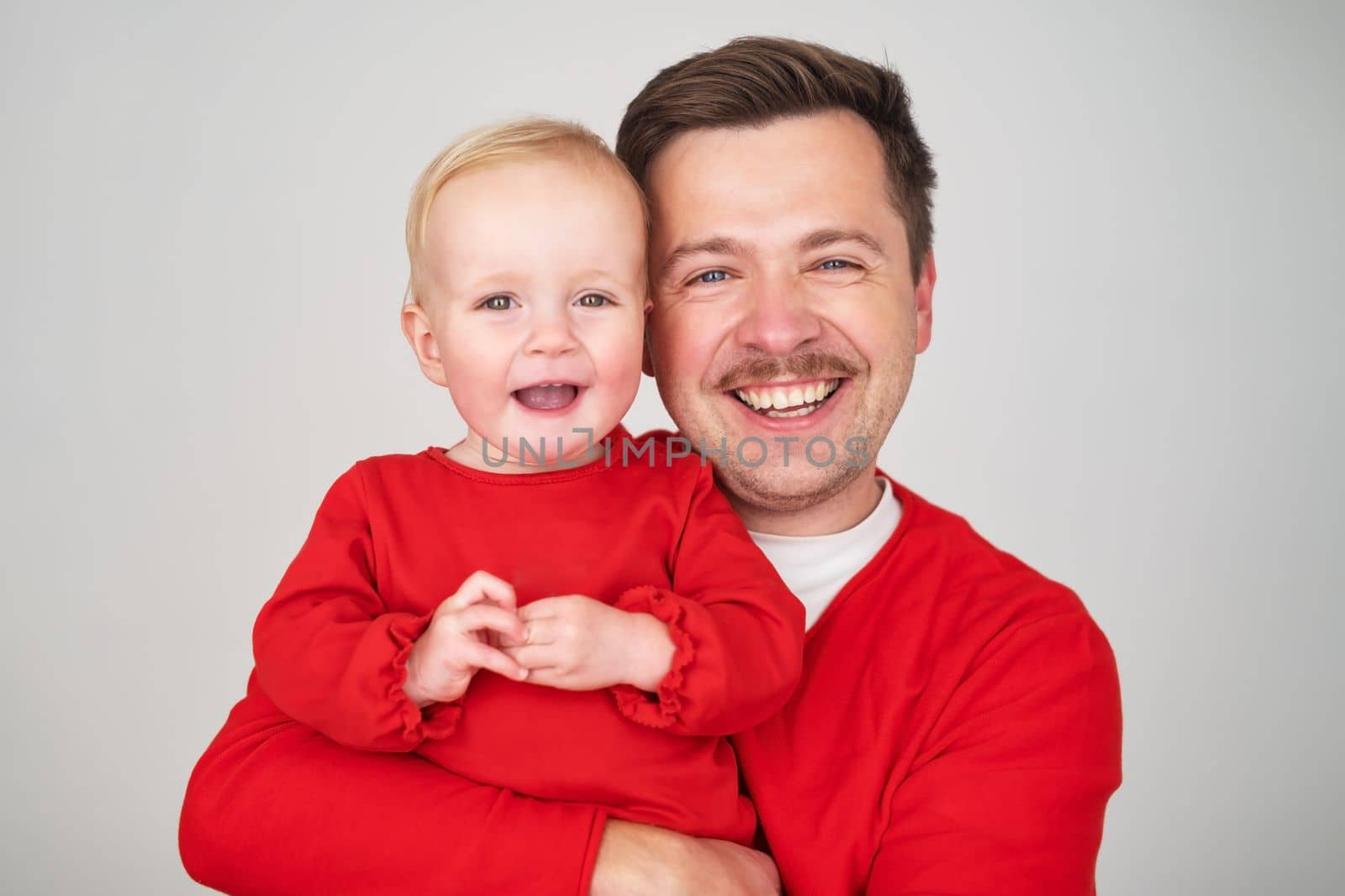 happy father holding his baby daughter smiling at camera. Studio shot