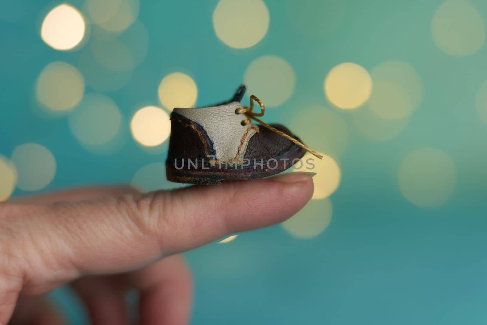 Cute little boots for teddy or doll on Christmas light background. Holiday glowing backdrop. Defocused Background With Blinking light. Blurred Bokeh. by Costin