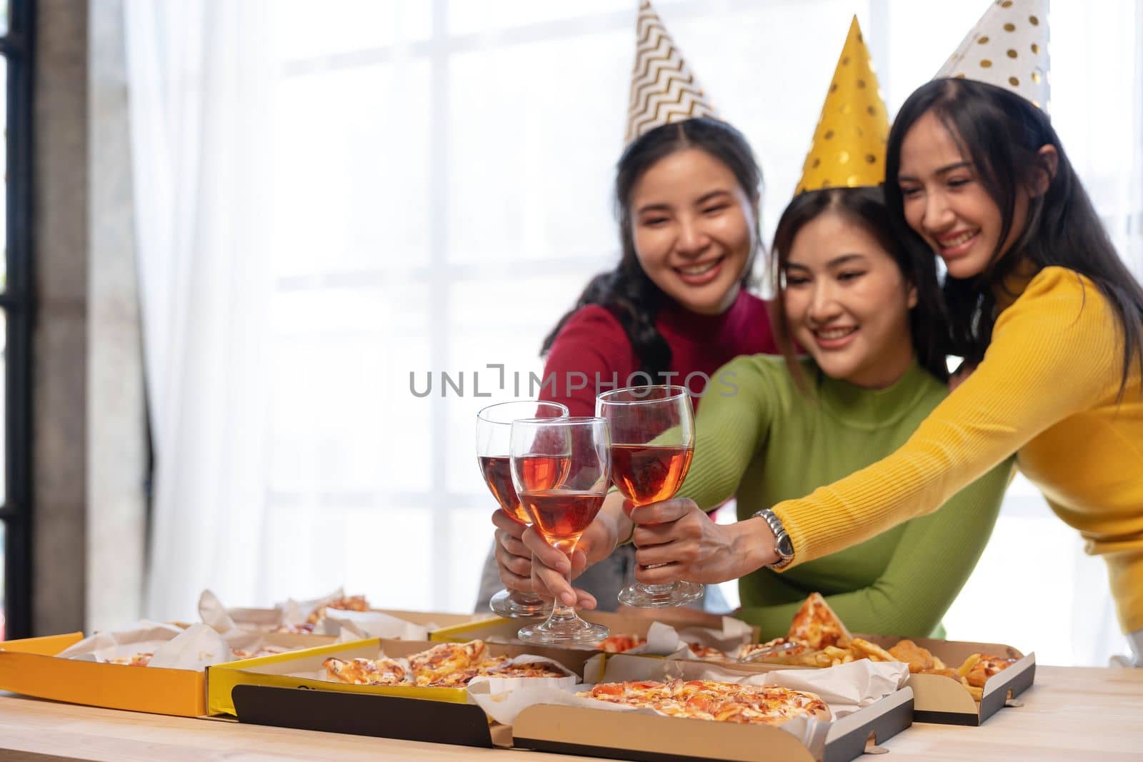 Group of happy young Asian people with friends celebrating clinking glasses during dinner party by wichayada