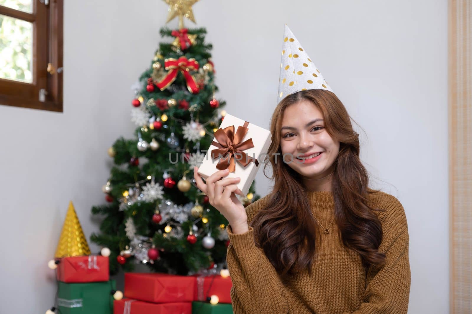 Merry Christmas and Happy Holidays Young woman with a beautiful face in a yellow shirt shows joy with gift boxes in a house