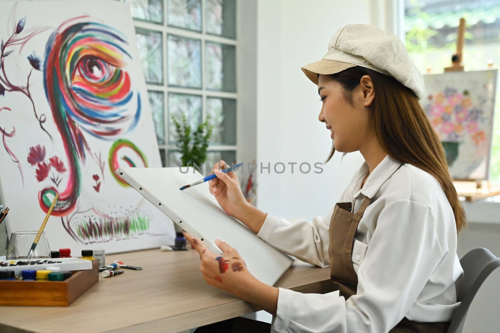 Young beautiful female artist painting on blank canvas. Hobby, art and people concept by prathanchorruangsak