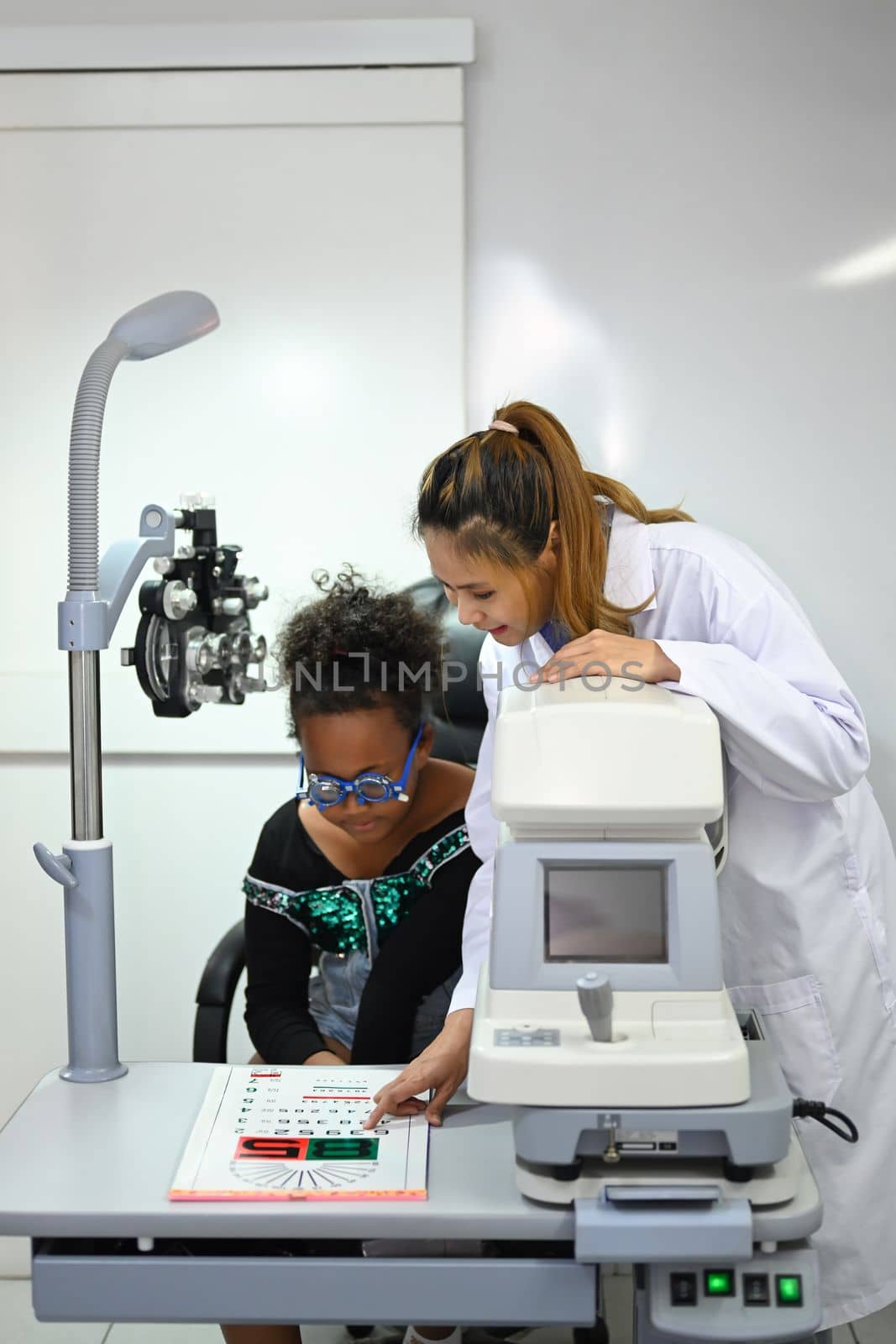 Ophthalmologist checking child eyesight with ophthalmology measurements letters, for testing visual acuity.