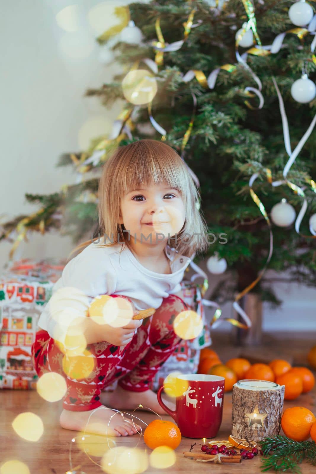 Charming child playing near the christmas tree.