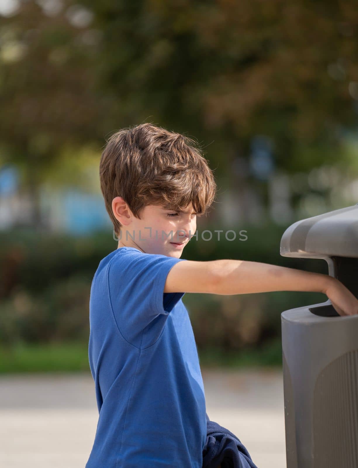 Caucasian kid 9 year old try to throw trash in public trashcan. Concept of garbage, Recycle environment, save world
