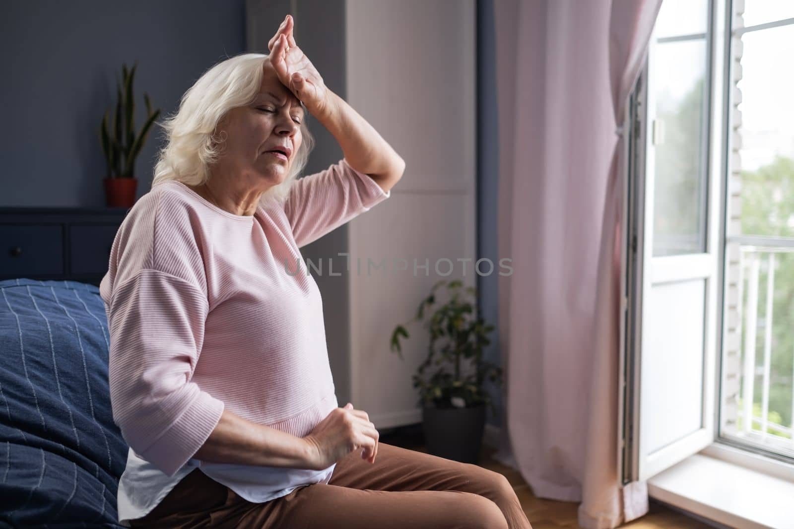 Senior caucasian woman suffering from a headache resting at home on sofa